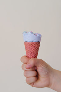 Hand holding ice cream cone against white background