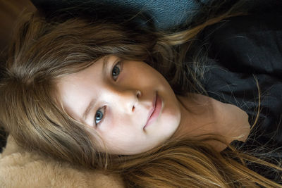 High angle portrait of girl lying on bed at home