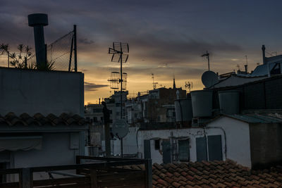 Houses in city against sky during sunset