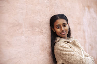 Portrait of teenage girl standing against wall