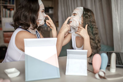 Mother and daughter wearing face mask while sitting at home