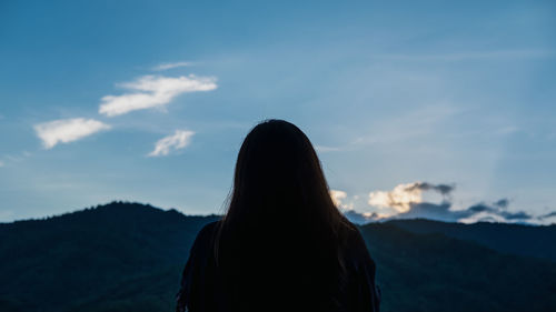 Rear view of woman standing on mountain against sky