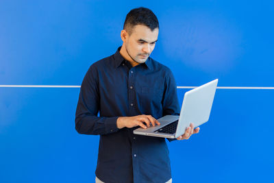 Man looking at camera while standing against blue sky