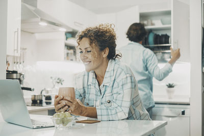 Young woman using mobile phone while sitting at home