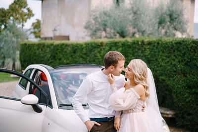Rear view of couple kissing against car