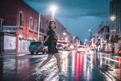 Portrait of smiling woman on wet street at night