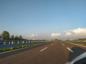 Road leading towards highway against blue sky