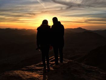 Silhouette men standing on desert against sky during sunset