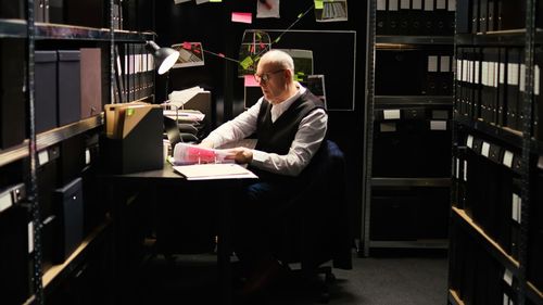 Side view of woman using mobile phone while standing in library