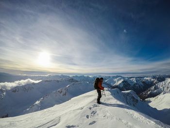 Side view of man on snow covered mountain against sky