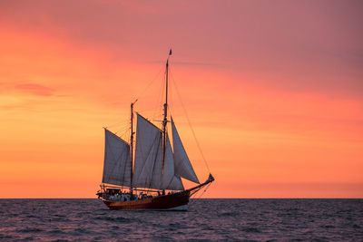 Ship sailing on sea against romantic sky at sunset