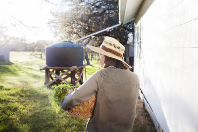 Female farmer carrying vegetables in basket at farm