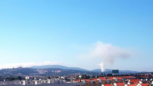 Smoke emitting from factory against clear blue sky