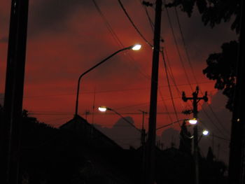 Silhouette trees and electricity pylon against sky at sunset