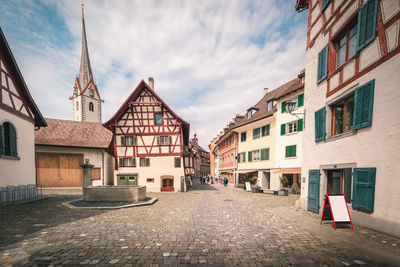 Empty street amidst buildings in town against sky