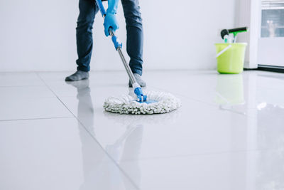 Low section of man cleaning floor at home