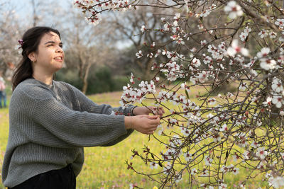 Side view of woman with pink flowers on tree