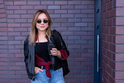 Portrait of young woman standing against wall