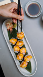 Eating sushi with chopsticks close up, food takeout and delivery service, salmon sushi rolls.