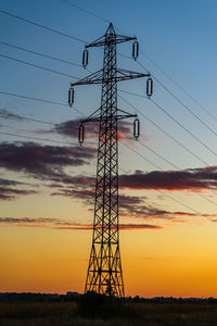 Low angle view of silhouette electricity pylon on field against sky
