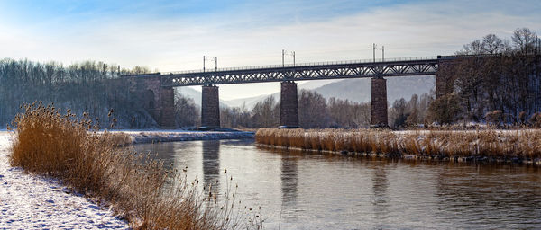 Bridge over river against sky during winter