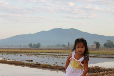 Portrait of cute girl standing against sky