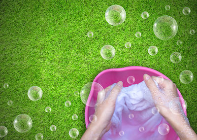 Cropped hands washing fabric in container