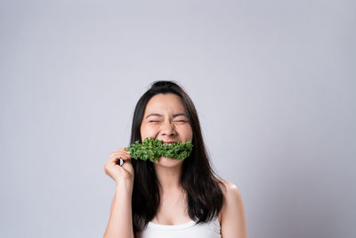 Portrait of woman holding ice cream against white background