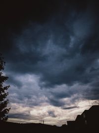 Low angle view of storm clouds over silhouette building