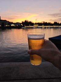 Cropped hand of woman holding beer glass