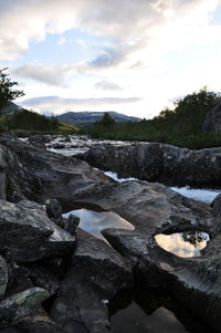 River flowing through rocks against sky