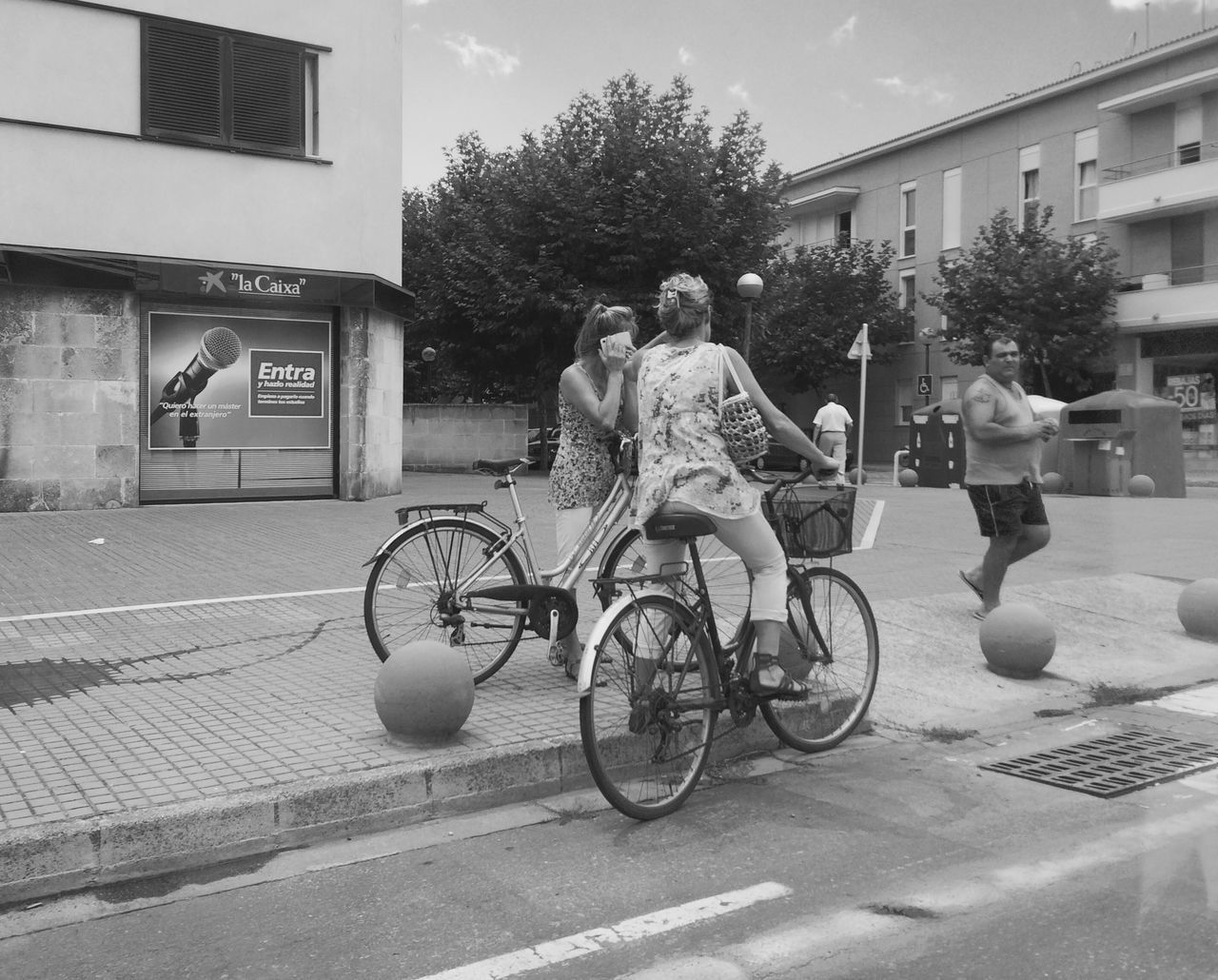 building exterior, architecture, bicycle, built structure, street, full length, lifestyles, transportation, land vehicle, city, mode of transport, leisure activity, men, sidewalk, outdoors, casual clothing, side view, tree