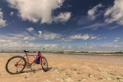 Bicycle on beach against sky