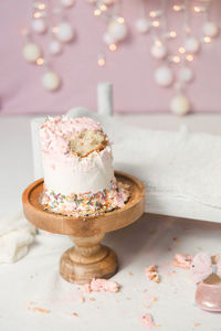 White and pink smashed cake next to little bed