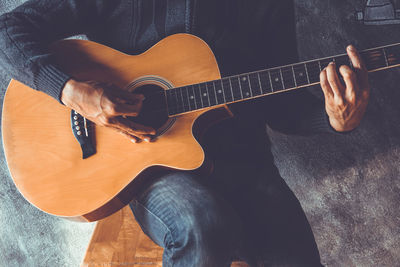 Midsection of man playing guitar against wall