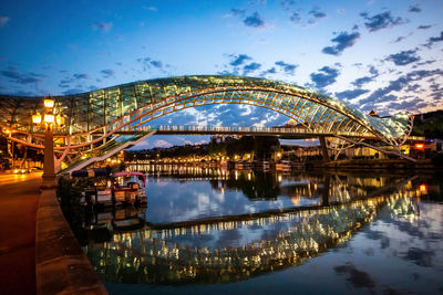 Illuminated bridge over river against sky in city