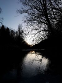 Silhouette trees by lake against sky during sunset