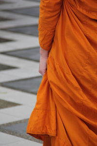 Midsection of monk wearing orange traditional clothing