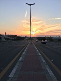 Cars on street against sky at sunset