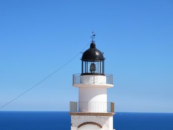 Lighthouse by sea against clear sky