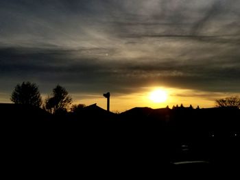 Silhouette trees on landscape against sky at sunset