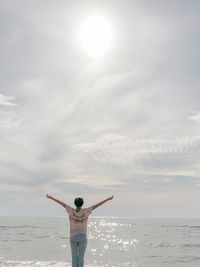 Full length of woman standing in sea against sky