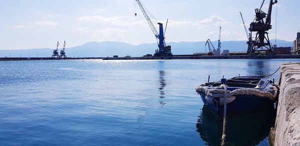 Sailboats moored at harbor against sky