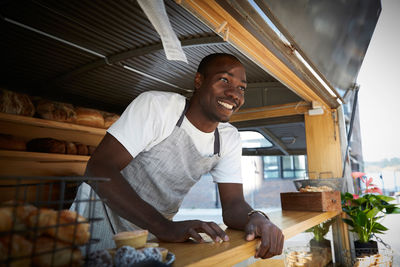 Smiling salesman looking away while standing in food truck