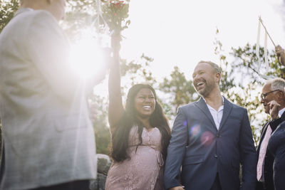 Young bride holding bouquet enjoying wedding ceremony with groom amidst guests