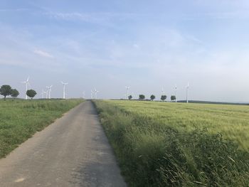 Road amidst field against sky