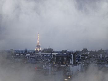 Buildings in city against cloudy sky