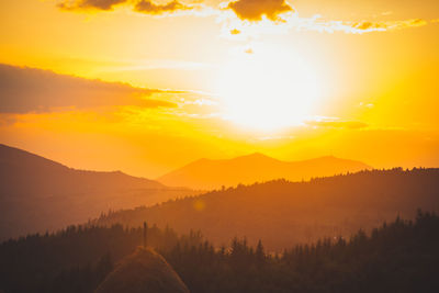 Scenic view of silhouette mountains against orange sky