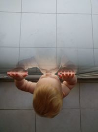 Midsection of woman holding umbrella on floor against wall