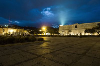 Illuminated buildings in town against sky at night